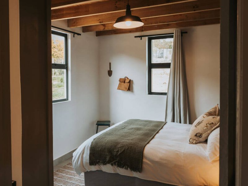 Bedroom with large window overlooking forest at De Stilte