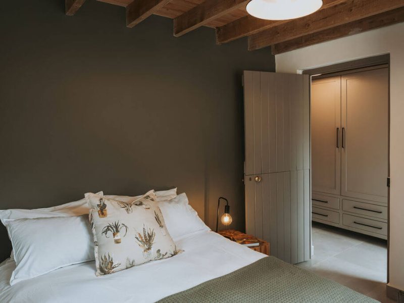 Bedroom with cream bedding and wooden ceiling beams at De Stilte