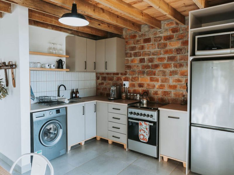 Bright cottage kitchen with washing machine and stove at De Stilte.