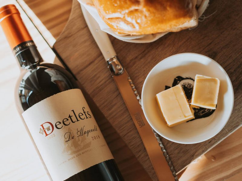 Bottle of wine, cheese and bread on a wooden breakfast table at De Stilte.