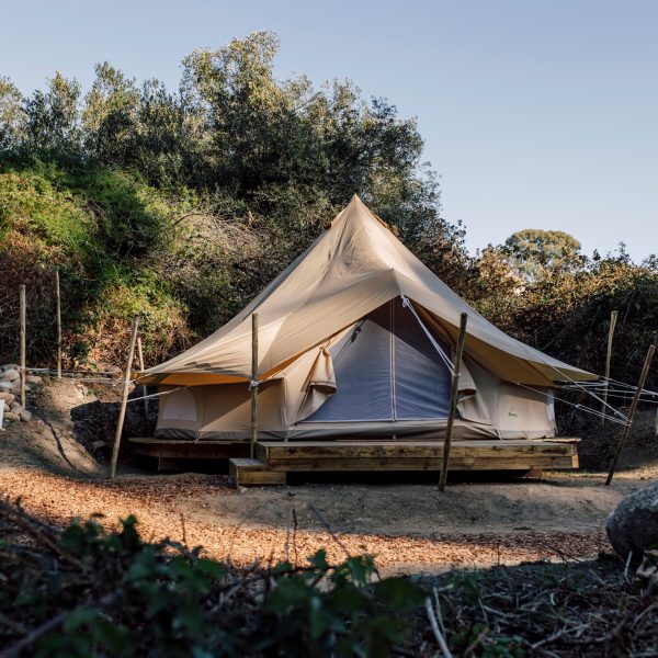 Canvas glamping tent on raised deck in a clearing