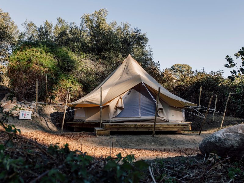 Canvas glamping tent on raised deck in a clearing