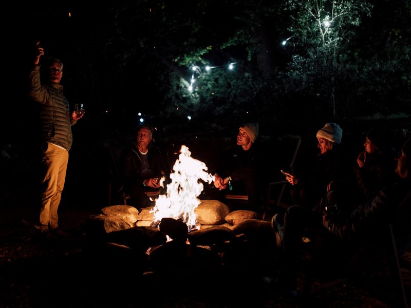 Friends gathered around a firepit at night at De Stilte
