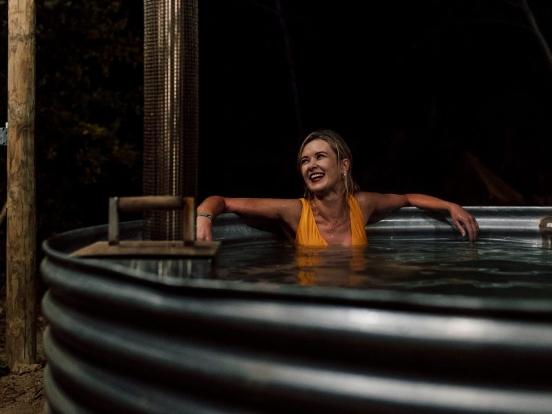 Guests in wood-fired hot tub laughing at night
