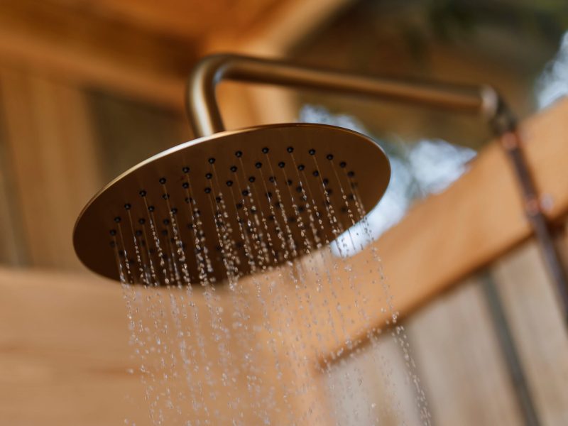 Rain shower head with water falling in warm light