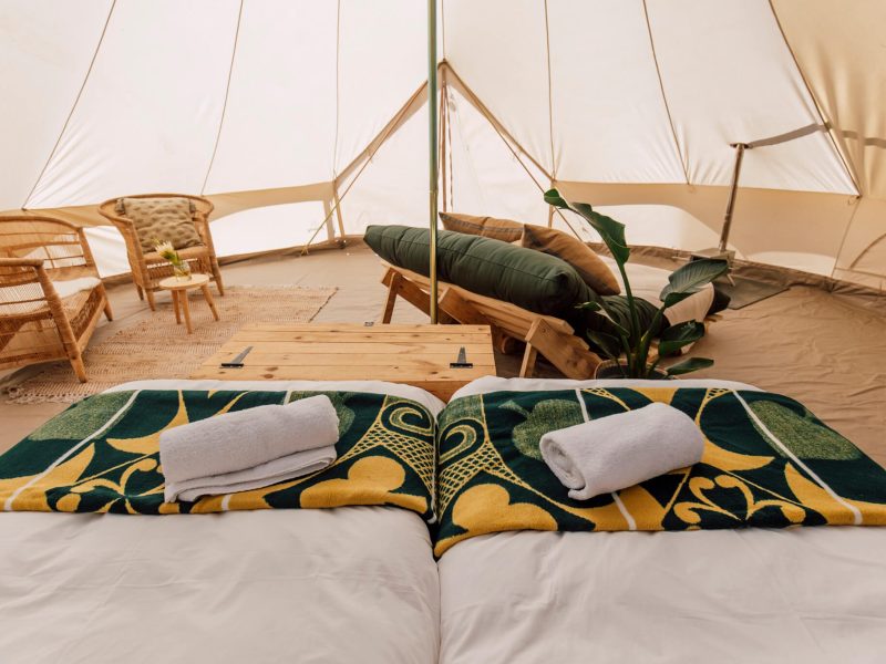 Rolled towels on patterned green throw at the foot of the bed