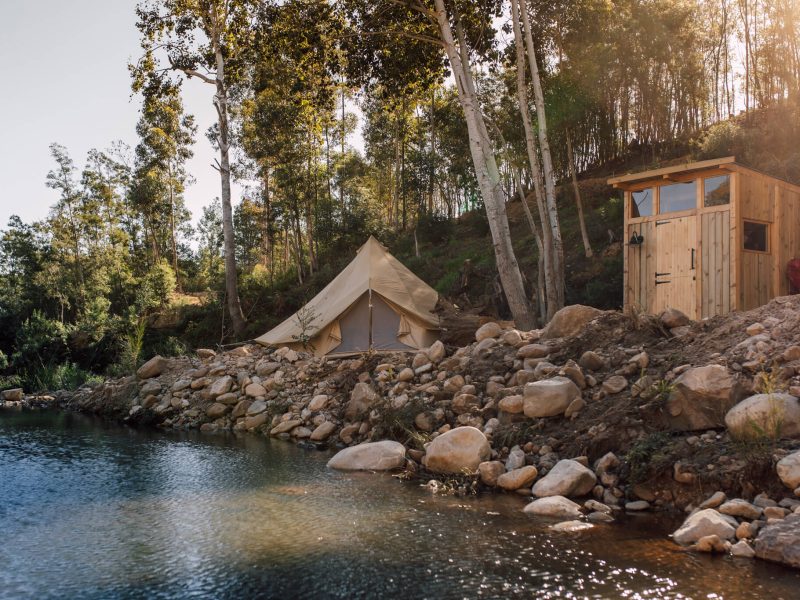 Riverside tent with stone cottage in the background
