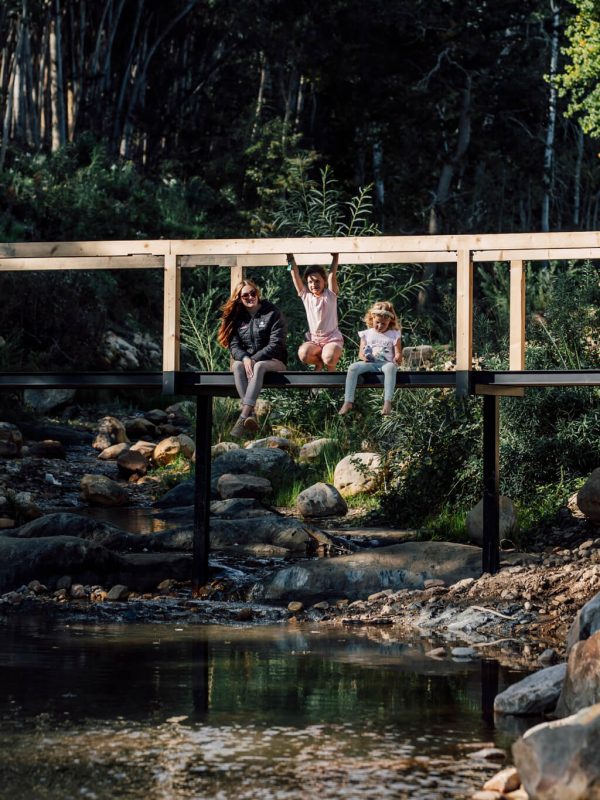 Footbridge over stream with guests seated on the bank