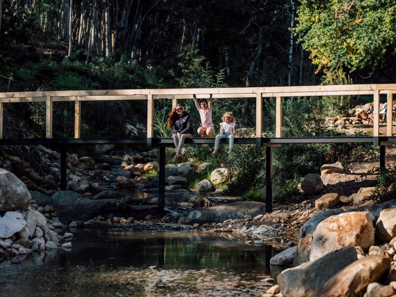 Footbridge over stream with guests seated on the bank